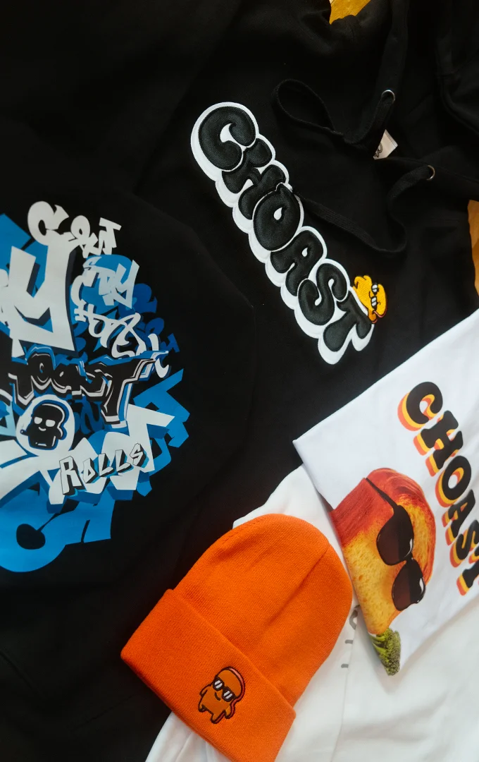 Our choast smoke accessories laying on a colorful beach towel. Showing our different products which are; Choast Plushie, choast bubble hoodie, choast n brocc tee, grafftee, and choast toque.